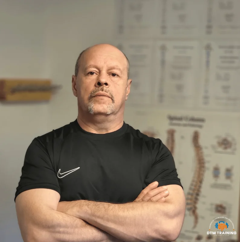 Daniel Batir, Personal Trainer and Sports Massage Therapist at DTM Training in London, standing with arms crossed in a training studio.