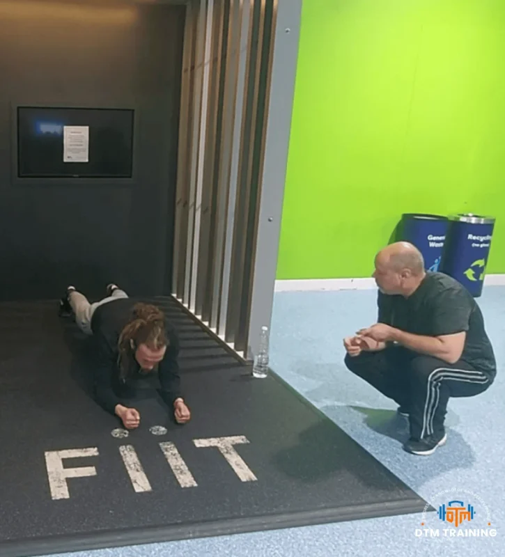 Personal trainer Daniel Batir coaching a client during a plank exercise to improve core strength and stability.