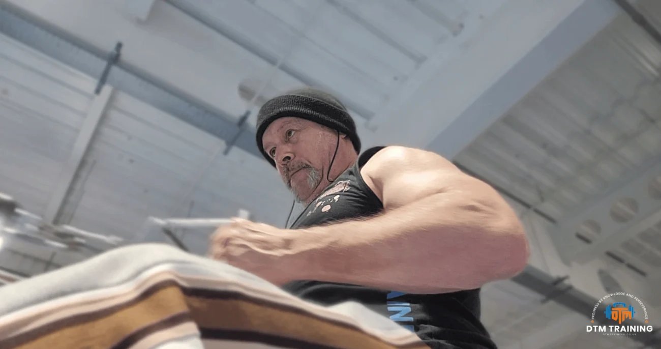 Daniel Batir performing a seated cable row exercise to develop upper back strength and posture in a London gym.