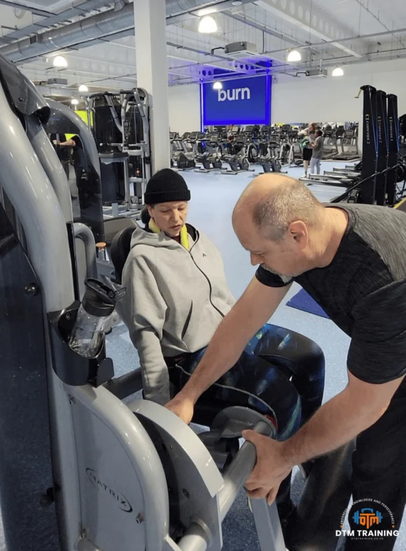 Daniel Batir coaching a client on a leg extension machine during a personalised personal training session in a commercial gym.