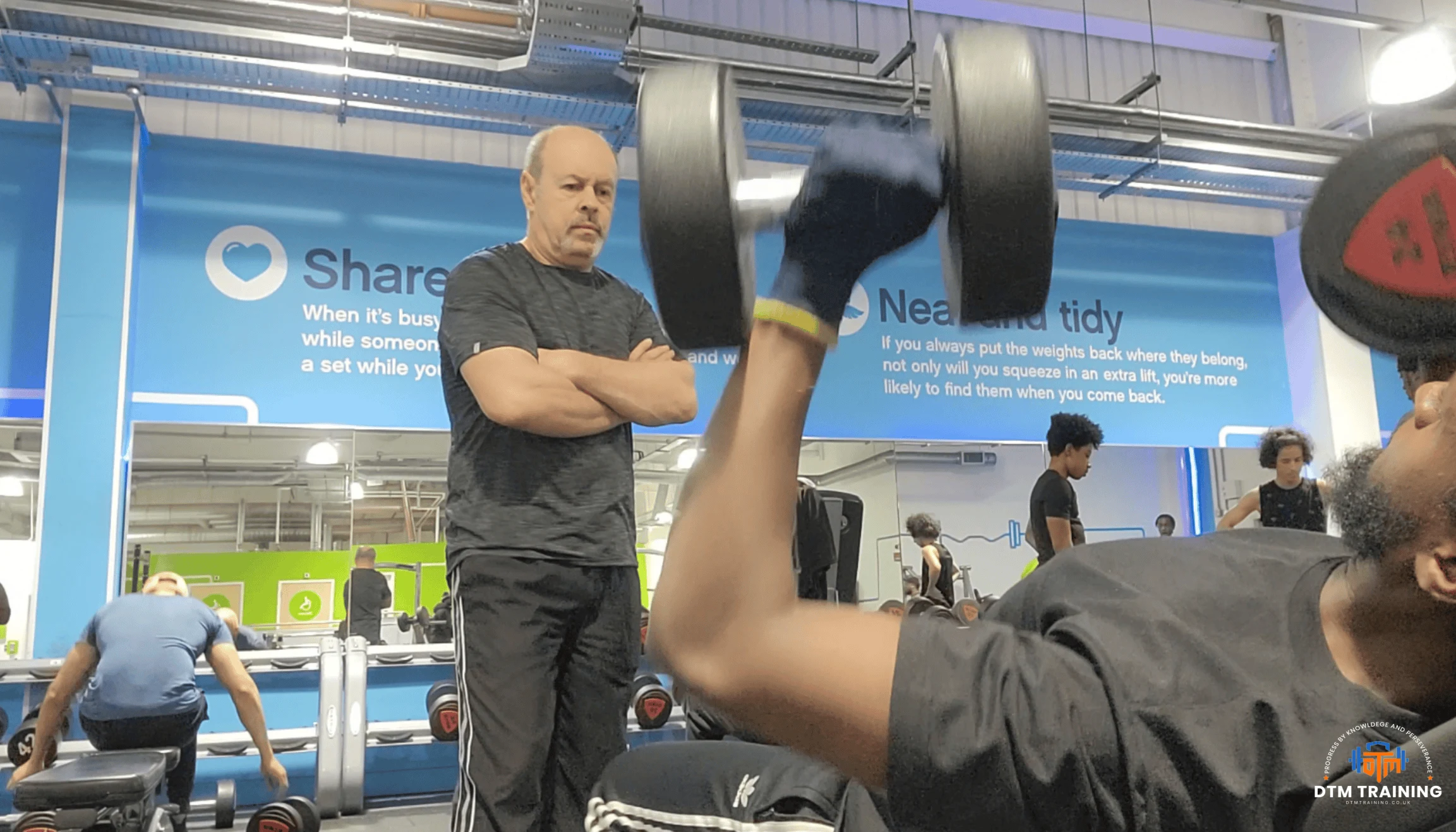 Daniel Batir coaching a client during a dumbbell strength training exercise in a London gym.