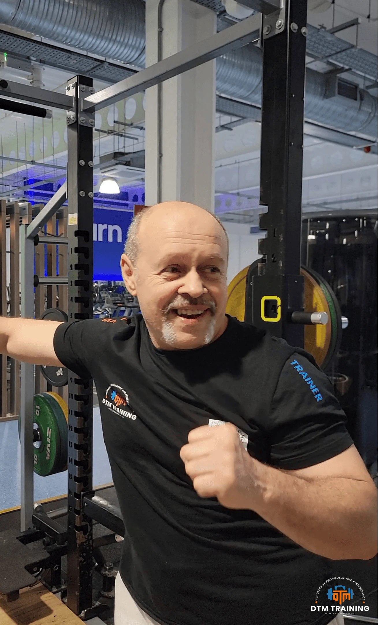 Daniel Batir, founder of DTM Training, smiling in a London gym during a training session.